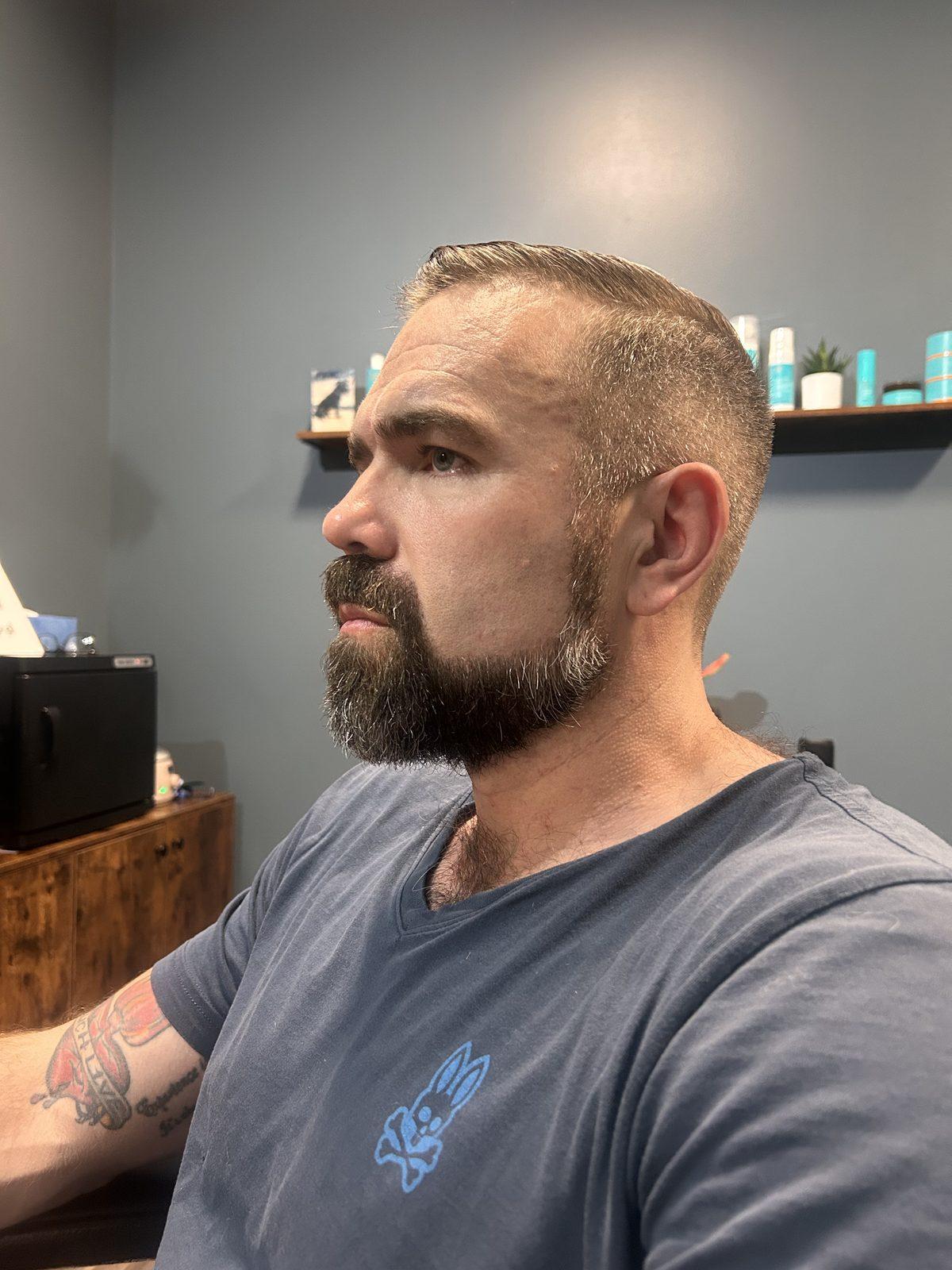 Comb-over swept back with a skin fade and a shaped beard